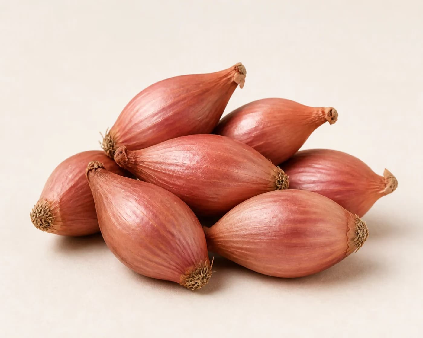 Fresh Shallots arranged on a warm off-white surface.