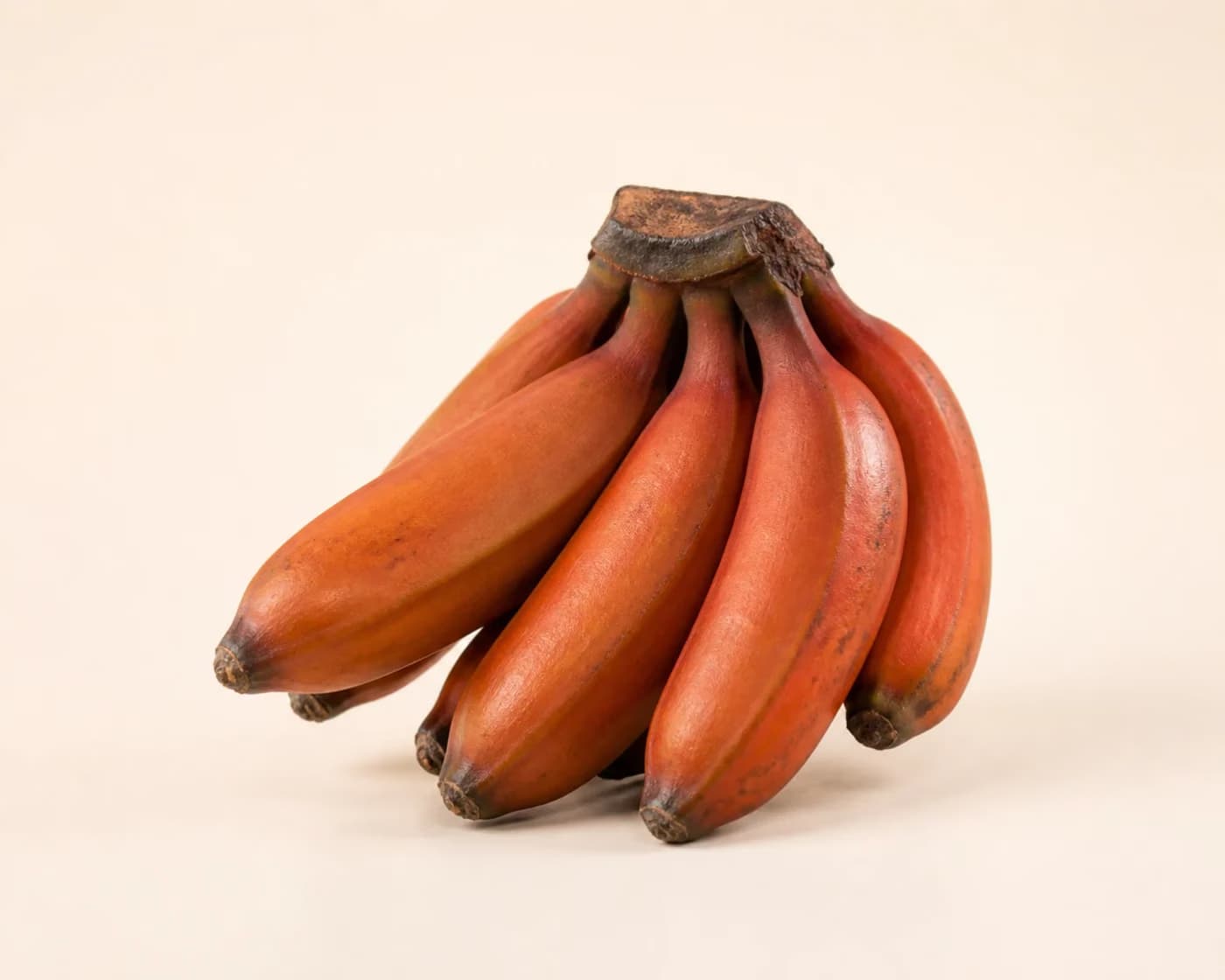 Fresh Red Banana arranged on a warm off-white surface.