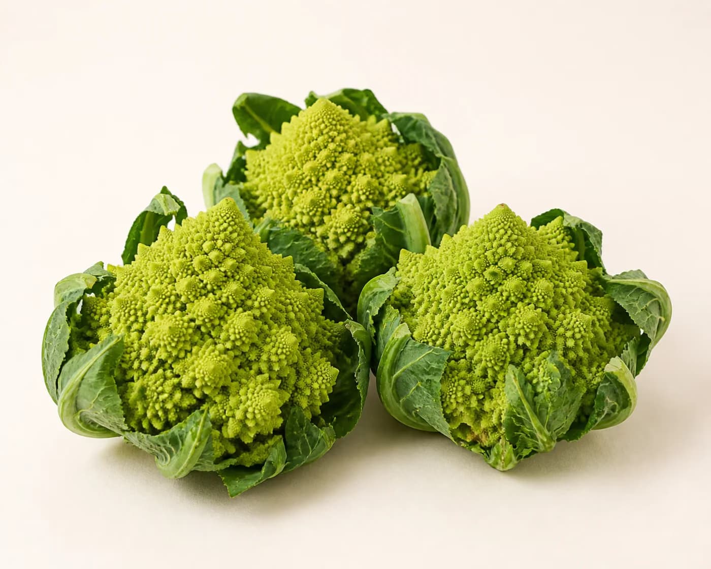 Fresh Romanesco arranged on a warm off-white surface.