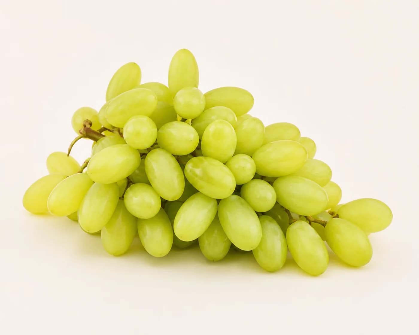 Fresh Sonaka Grapes arranged on a warm off-white surface.