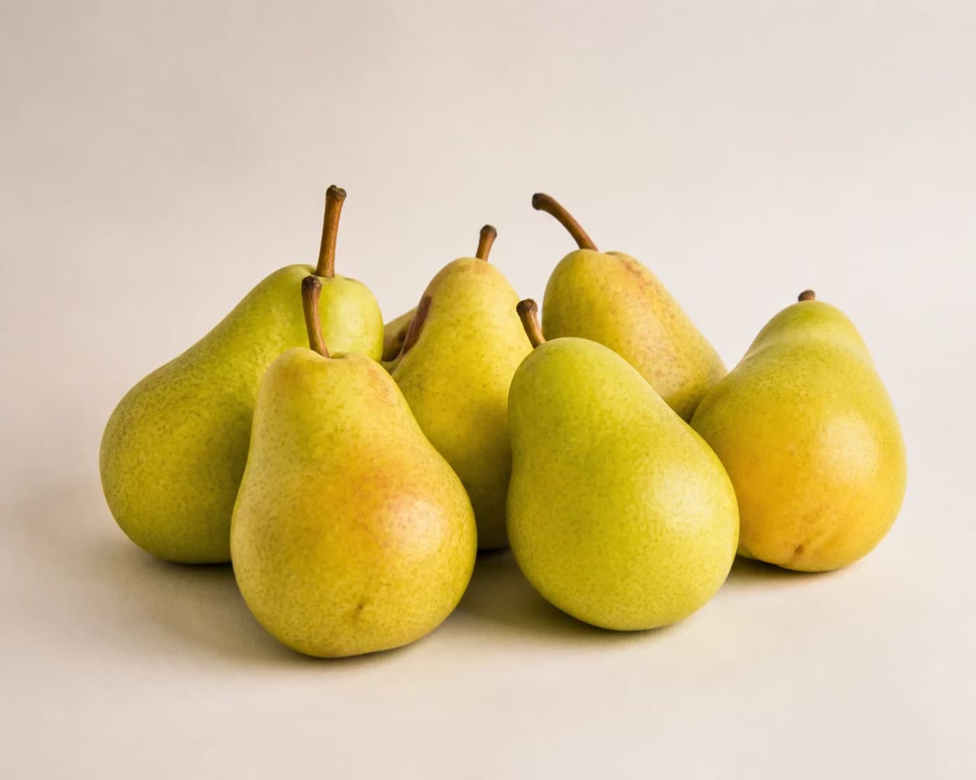 Fresh Bartlett Pear arranged on a warm off-white surface.