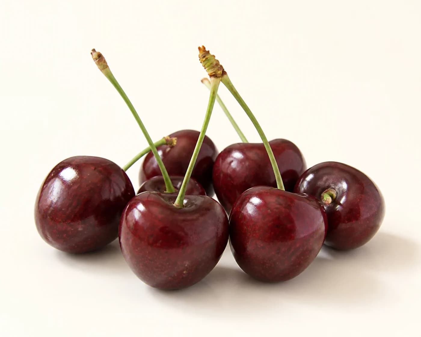 Fresh Dark Sweet Cherry arranged on a warm off-white surface.