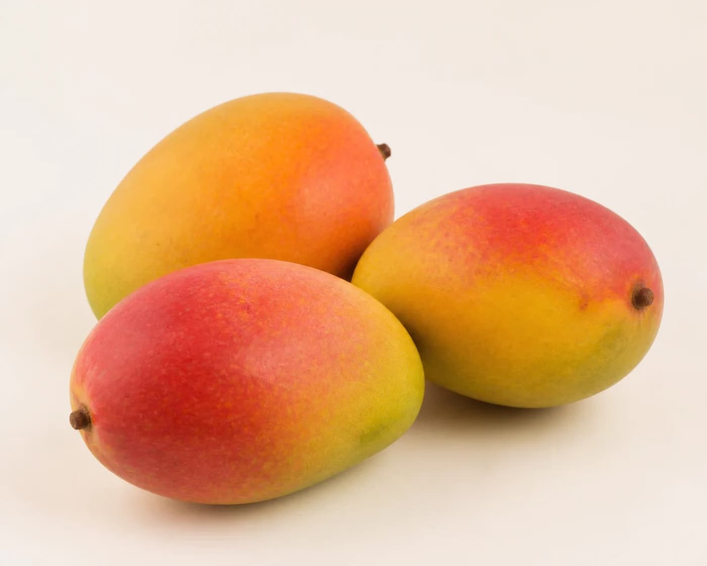 Fresh Sindhura Mango arranged on a warm off-white surface.