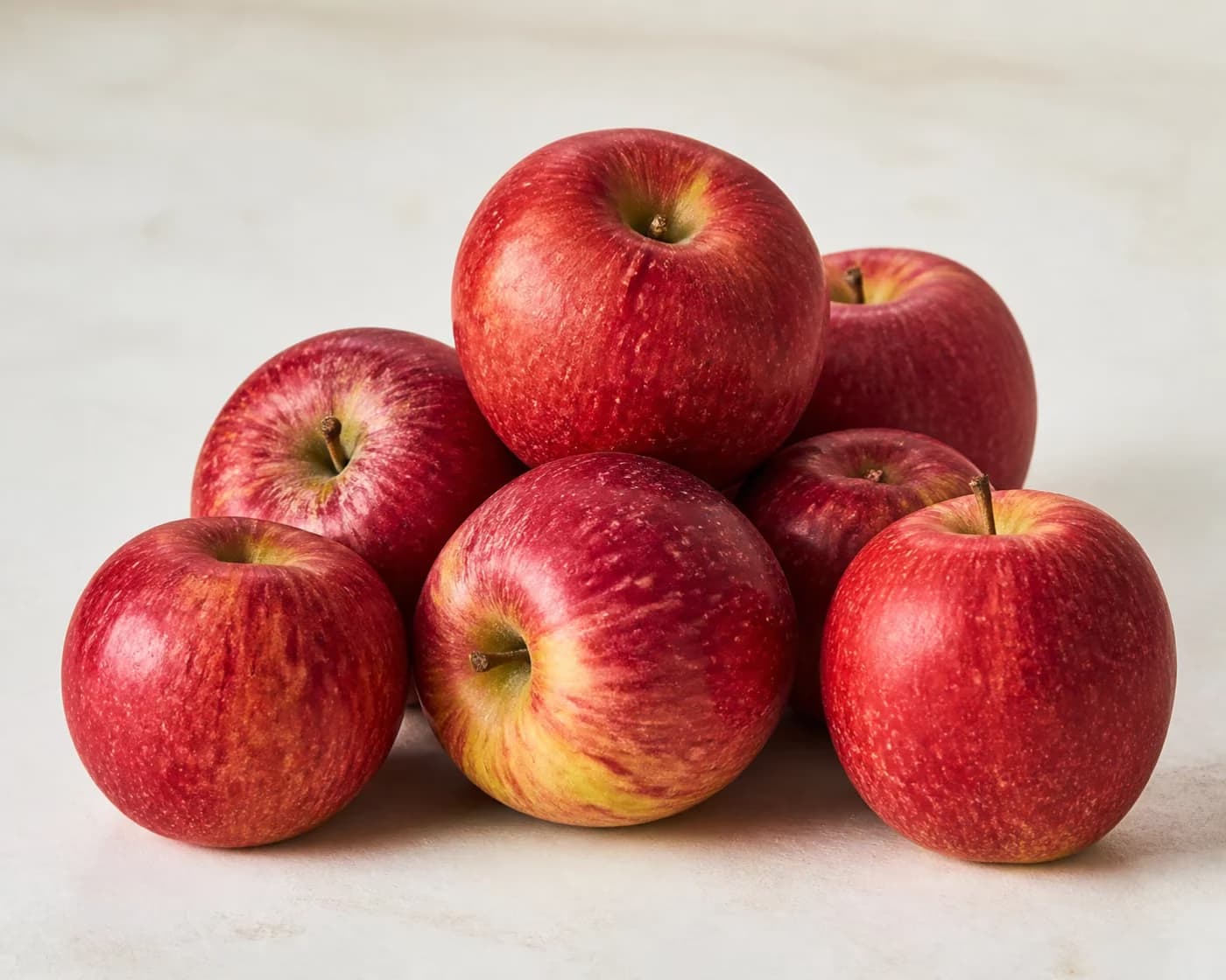 Fresh Kinnaur Apple arranged on a warm off-white surface.