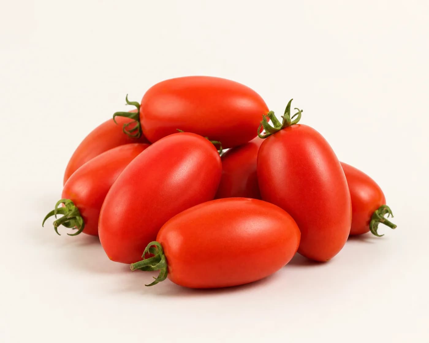 Fresh Roma Tomato arranged on a warm off-white surface.