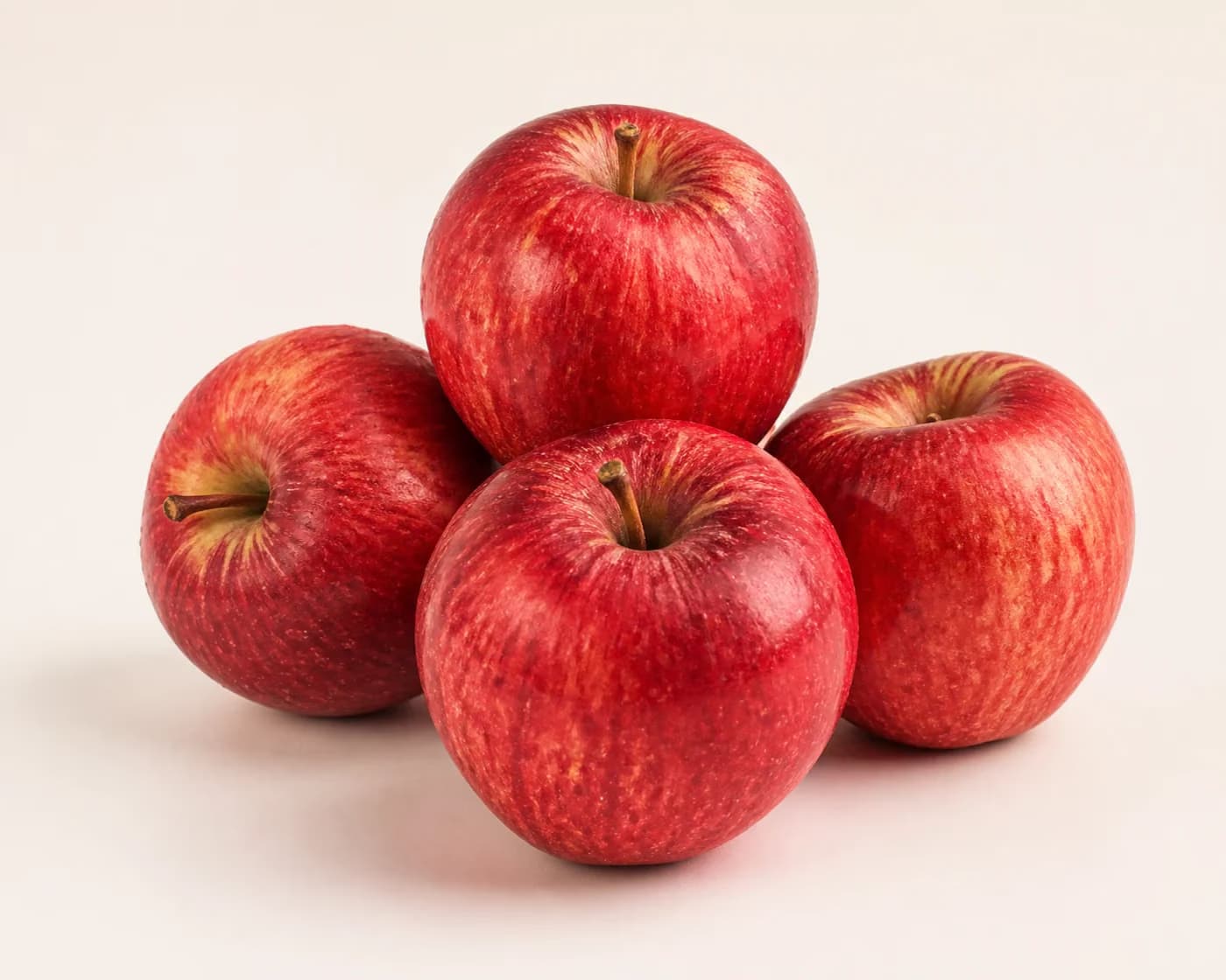 Fresh Himachali Royal Delicious apples arranged on a warm off-white surface.