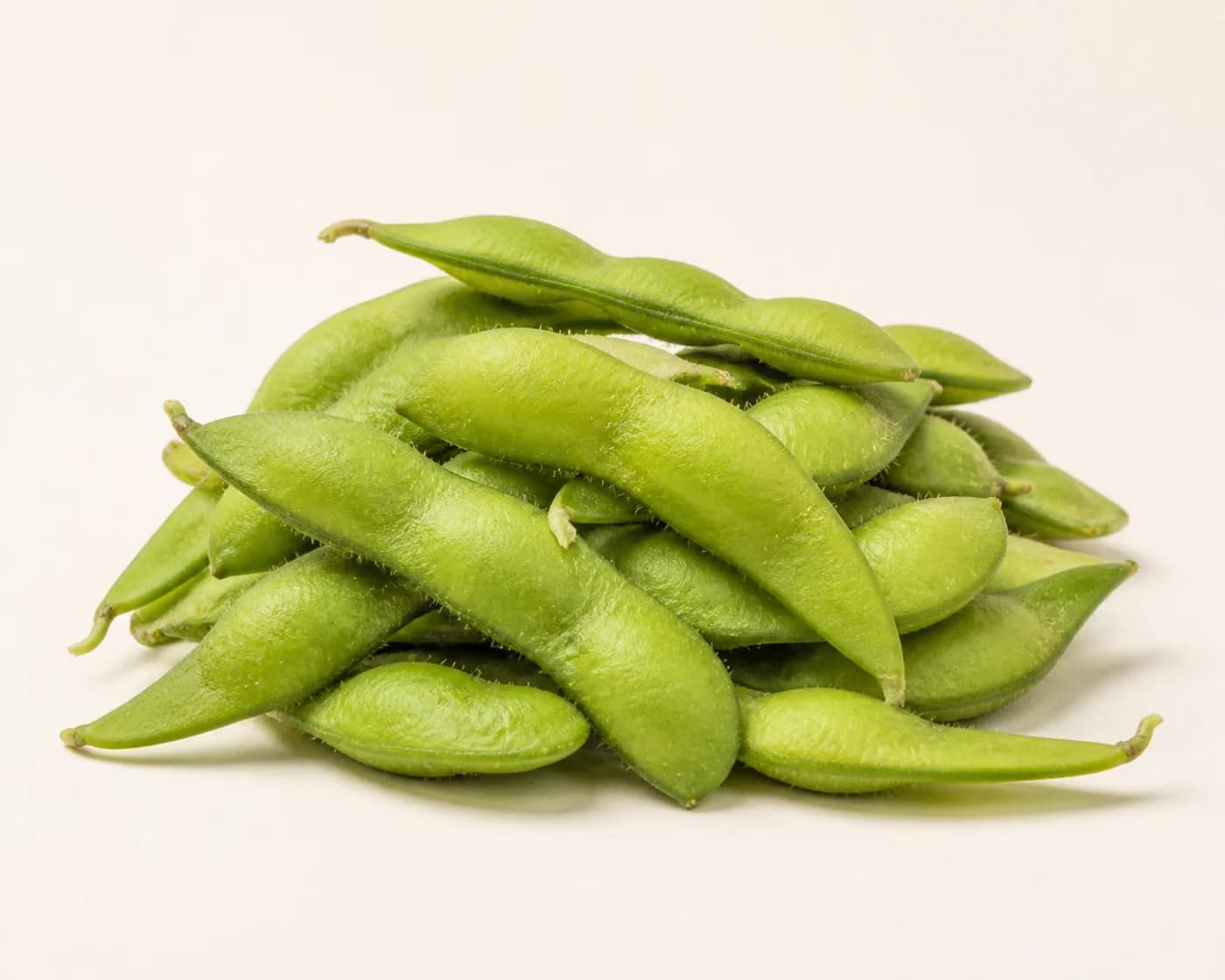 Fresh Edamame arranged on a warm off-white surface.