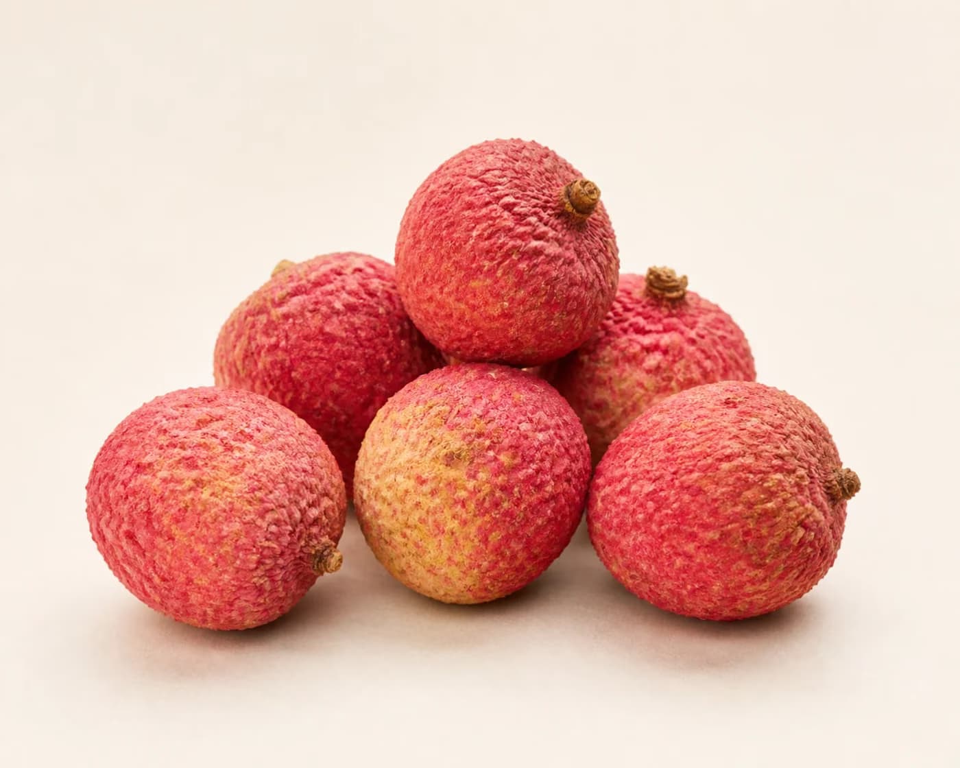 Fresh Shahi Litchi arranged on a warm off-white surface.