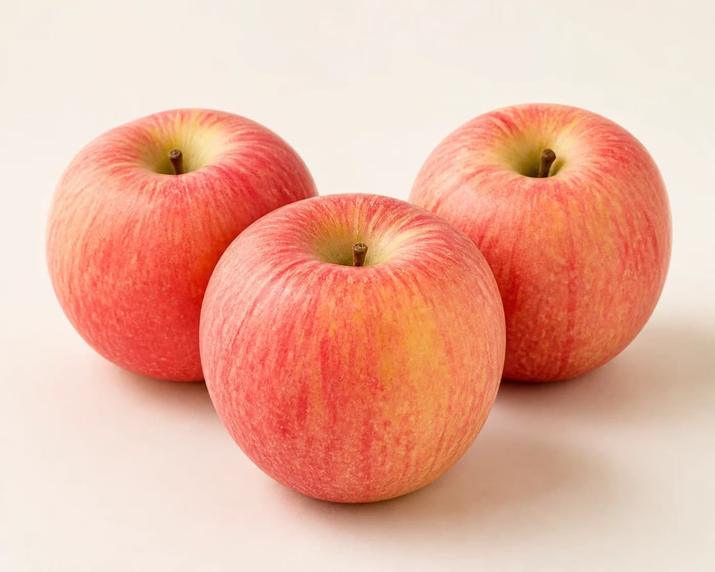 Fresh Cripps Pink Apple arranged on a warm off-white surface.