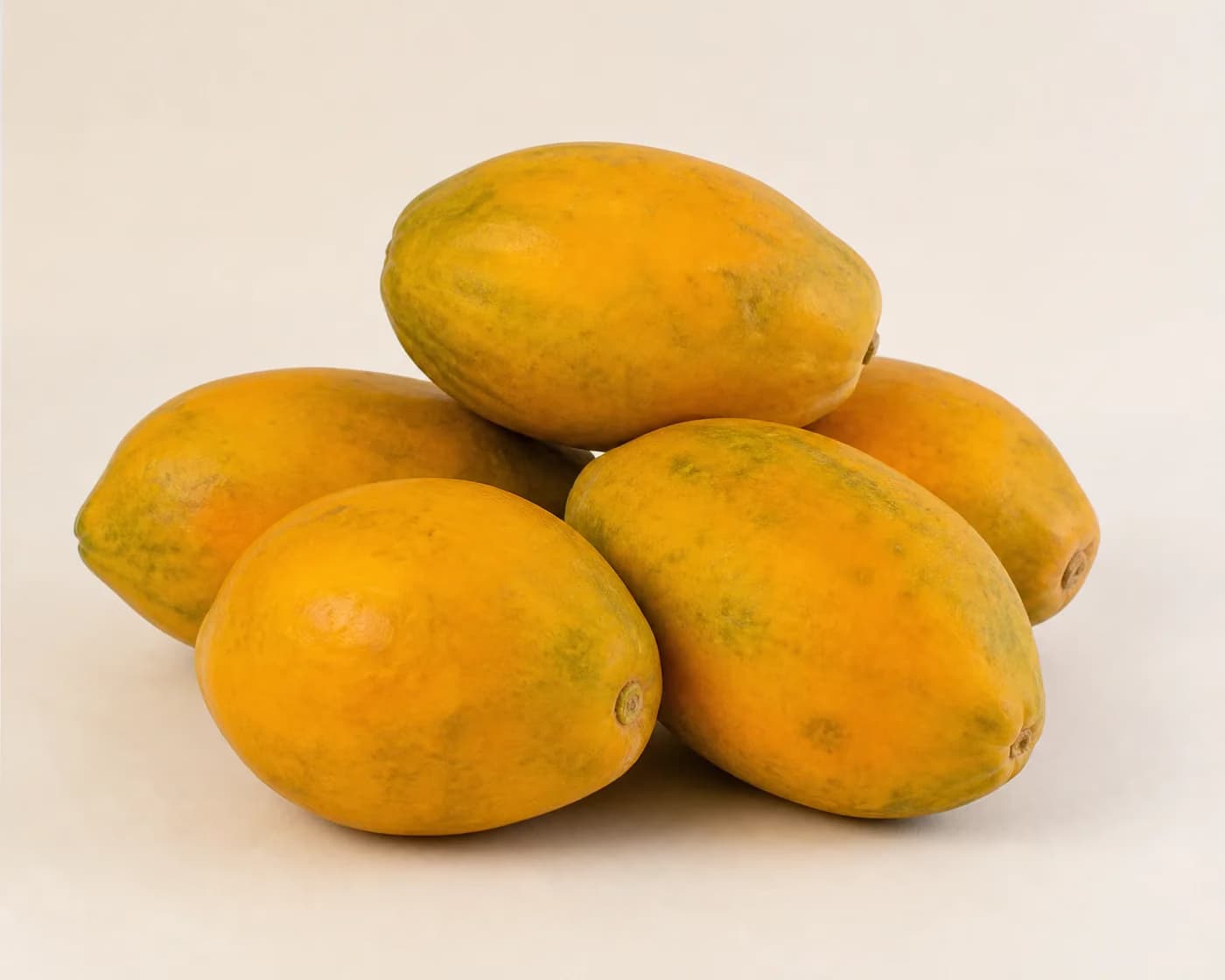 Fresh Pusa Delicious Papaya arranged on a warm off-white surface.