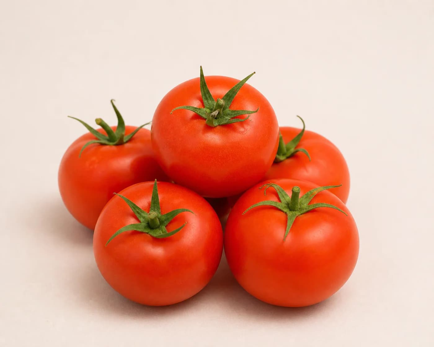 Fresh Hybrid Tomato arranged on a warm off-white surface.