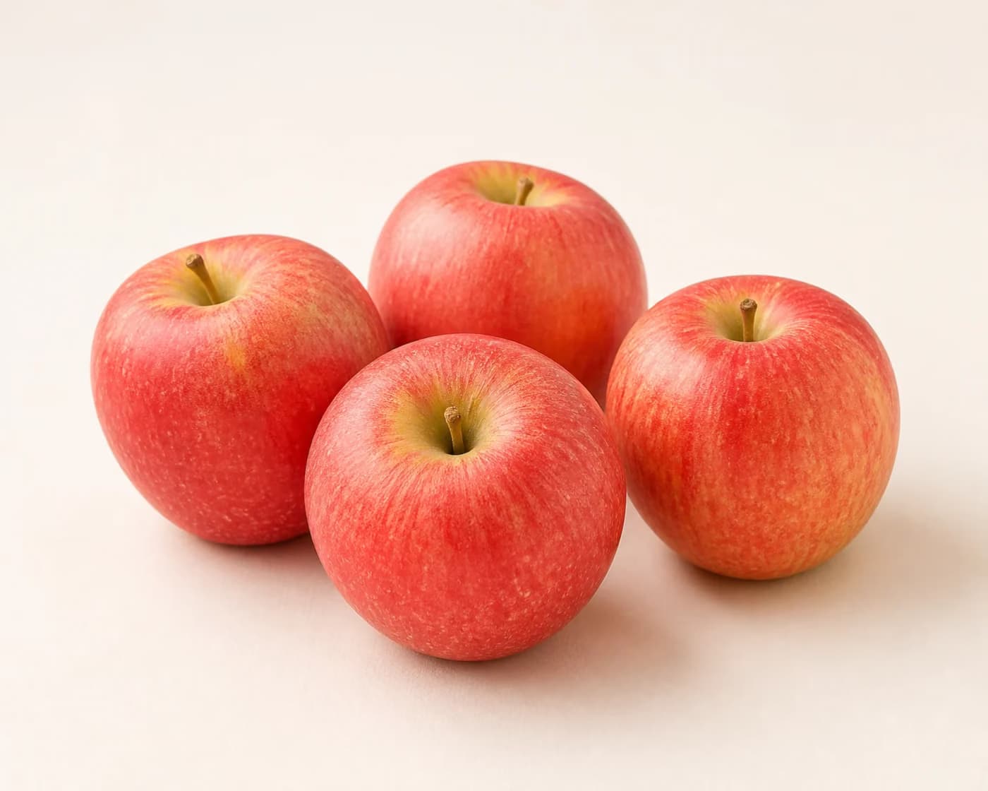 Fresh Fuji Apple arranged on a warm off-white surface.