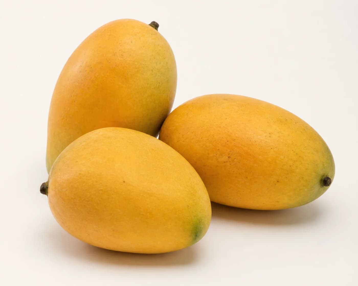 Fresh Amrapali Mango arranged on a warm off-white surface.