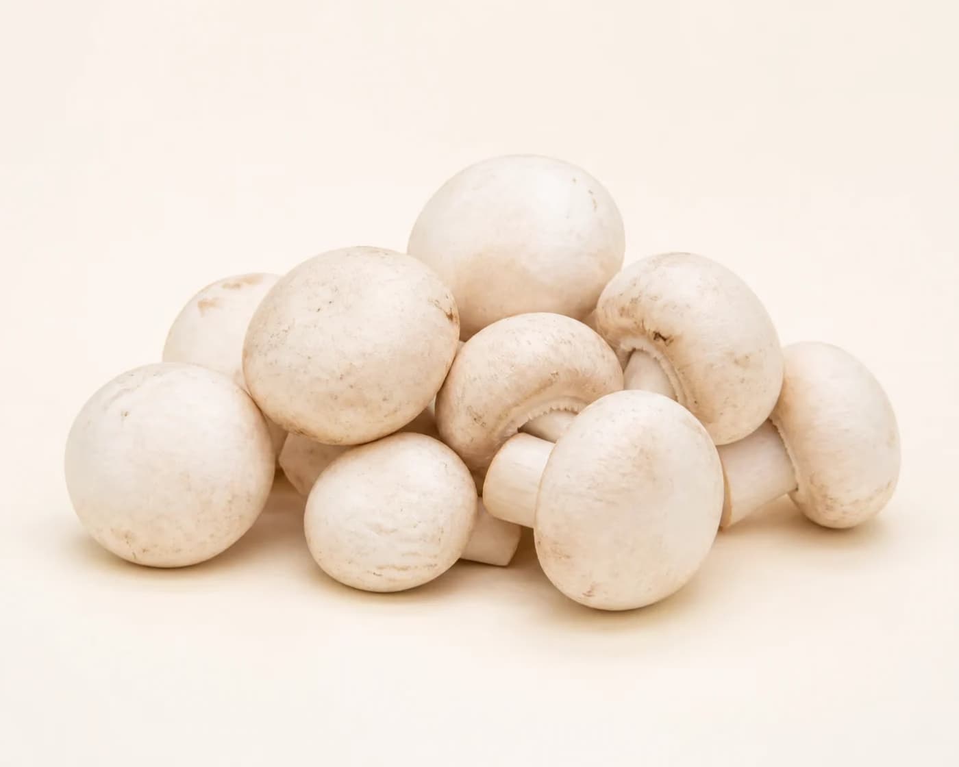 Fresh Button Mushroom arranged on a warm off-white surface.