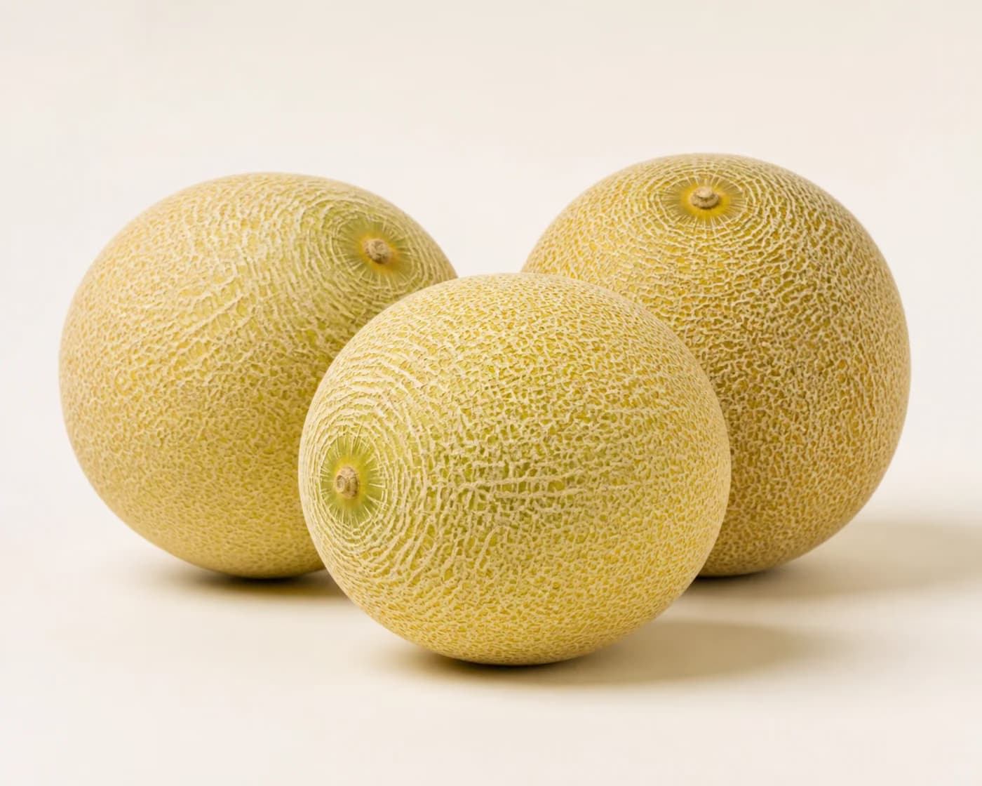 Fresh Galia Melon arranged on a warm off-white surface.