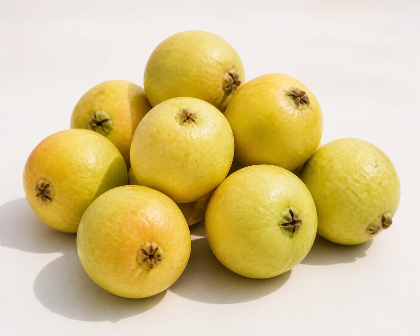 Fresh CISH Lalit Guava arranged on a warm off-white surface.
