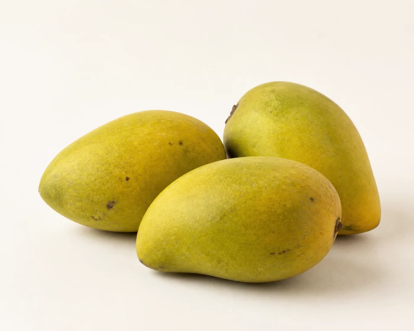 Fresh Imam Pasand Mango arranged on a warm off-white surface.