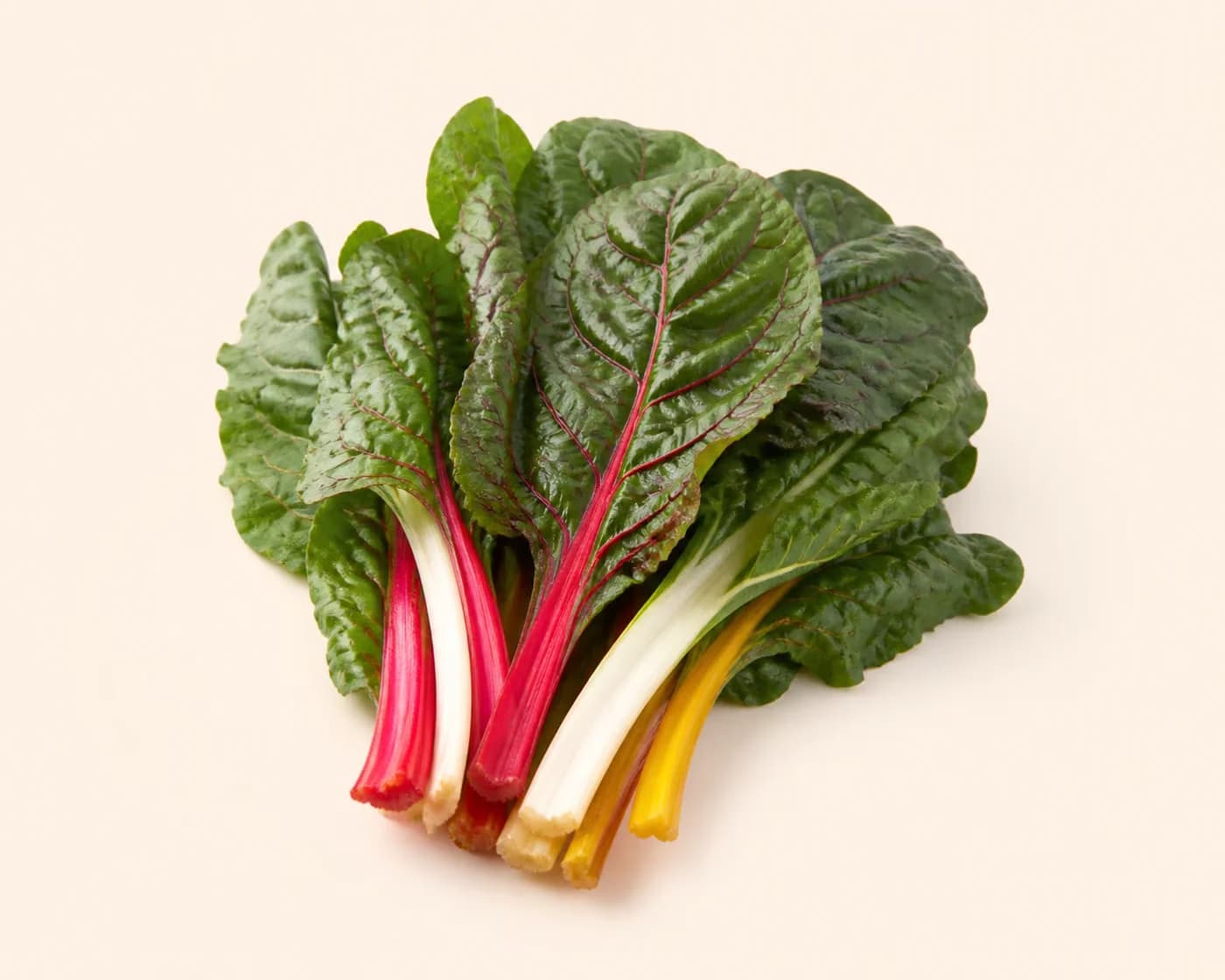 Fresh Swiss Chard arranged on a warm off-white surface.