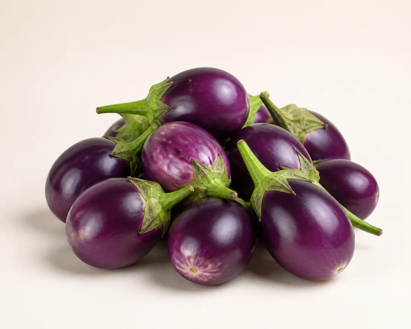 Fresh Small Purple Brinjal arranged on a warm off-white surface.