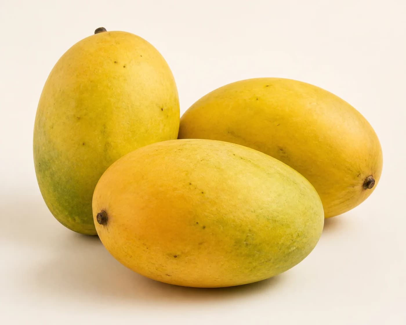 Fresh Fazli Mango arranged on a warm off-white surface.