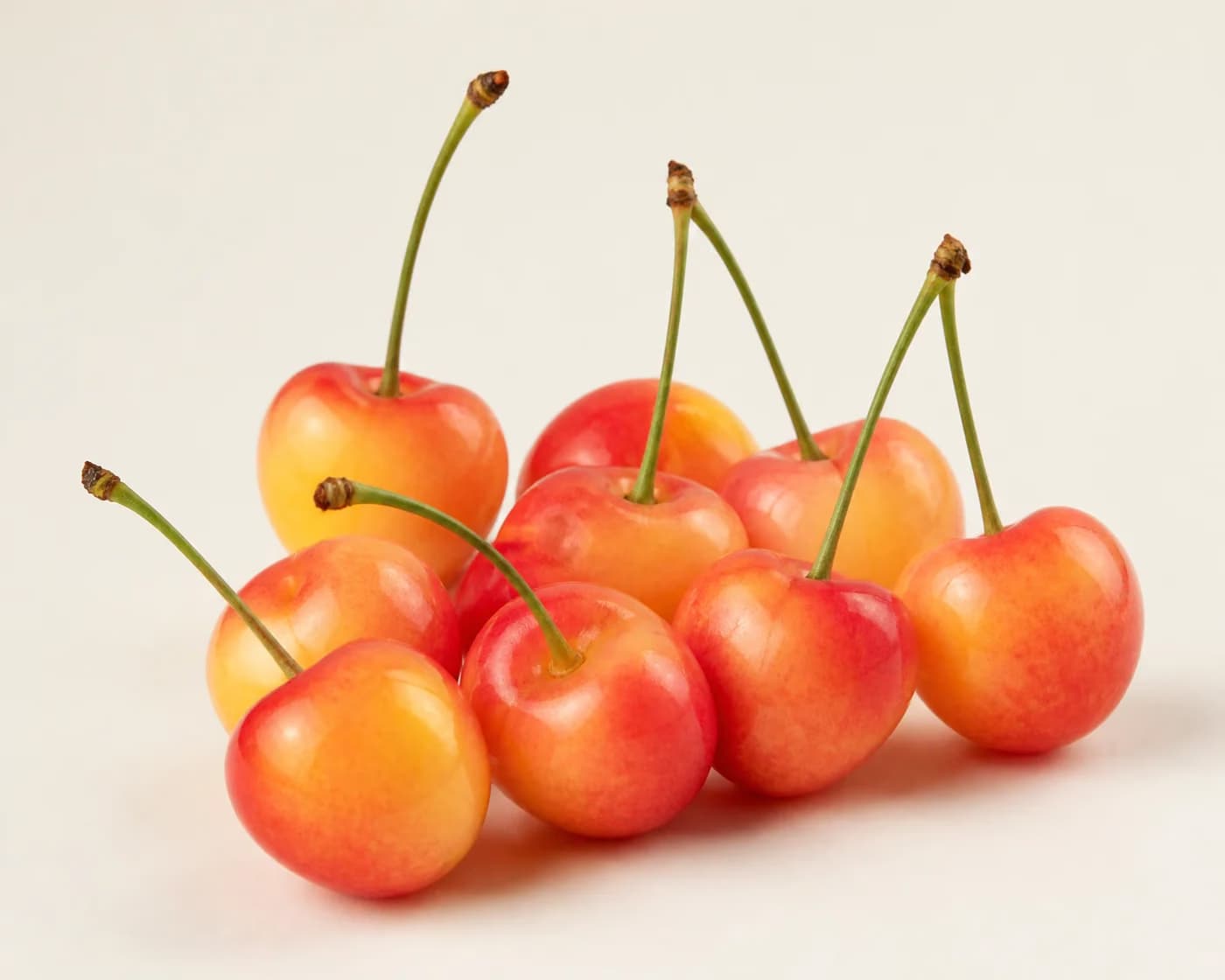 Fresh Rainier Cherry arranged on a warm off-white surface.