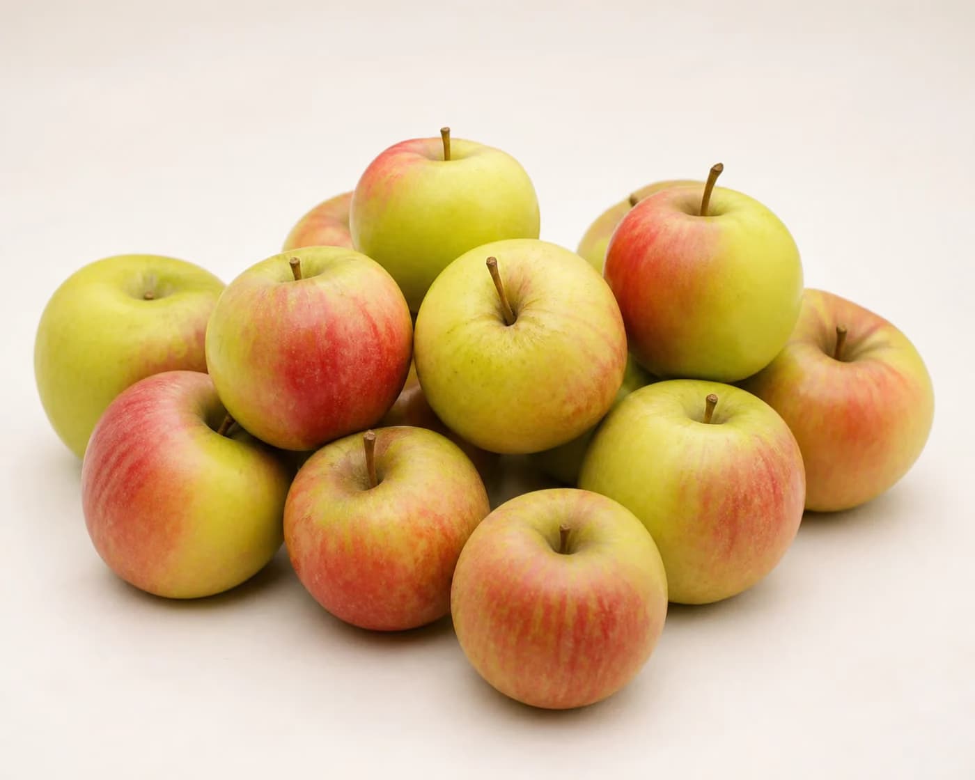 Fresh Kashmiri Ambri Apple arranged on a warm off-white surface.