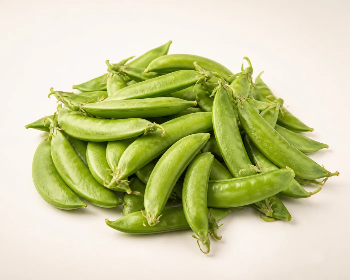 Fresh Sugar Snap Peas arranged on a warm off-white surface.