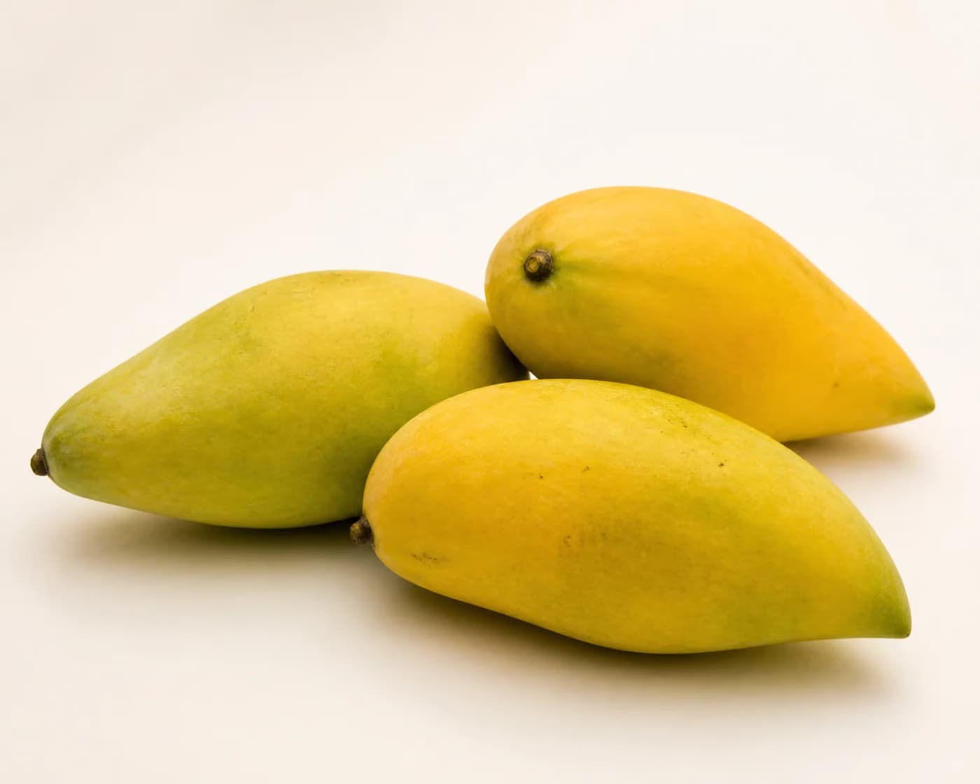 Fresh Totapuri Mango arranged on a warm off-white surface.