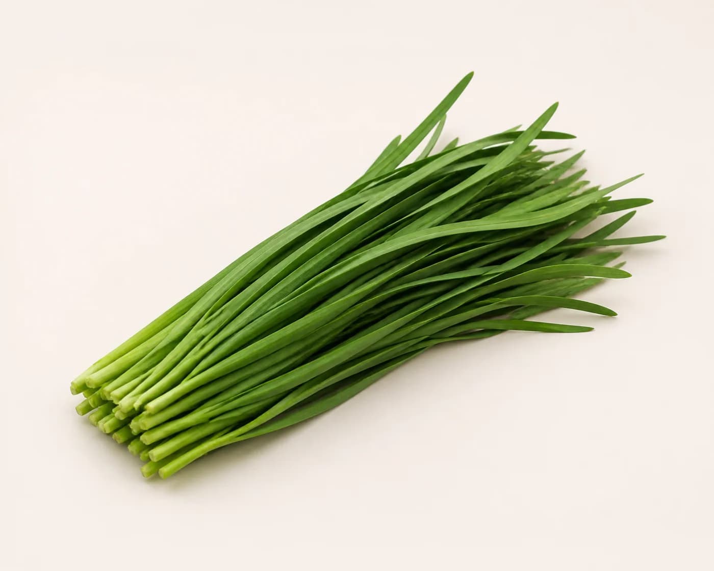 Fresh Garlic Chives arranged on a warm off-white surface.