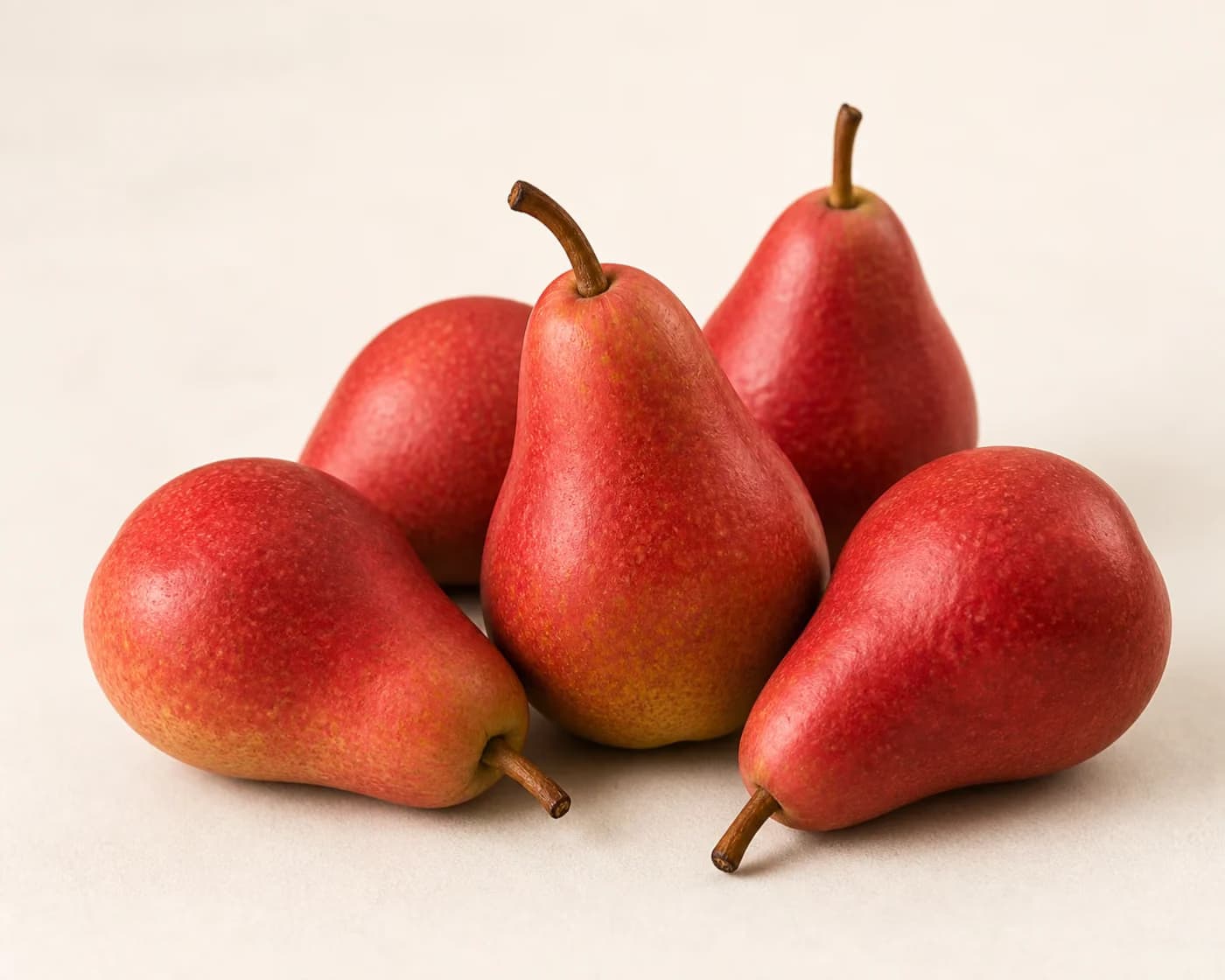 Fresh Red Pear arranged on a warm off-white surface.