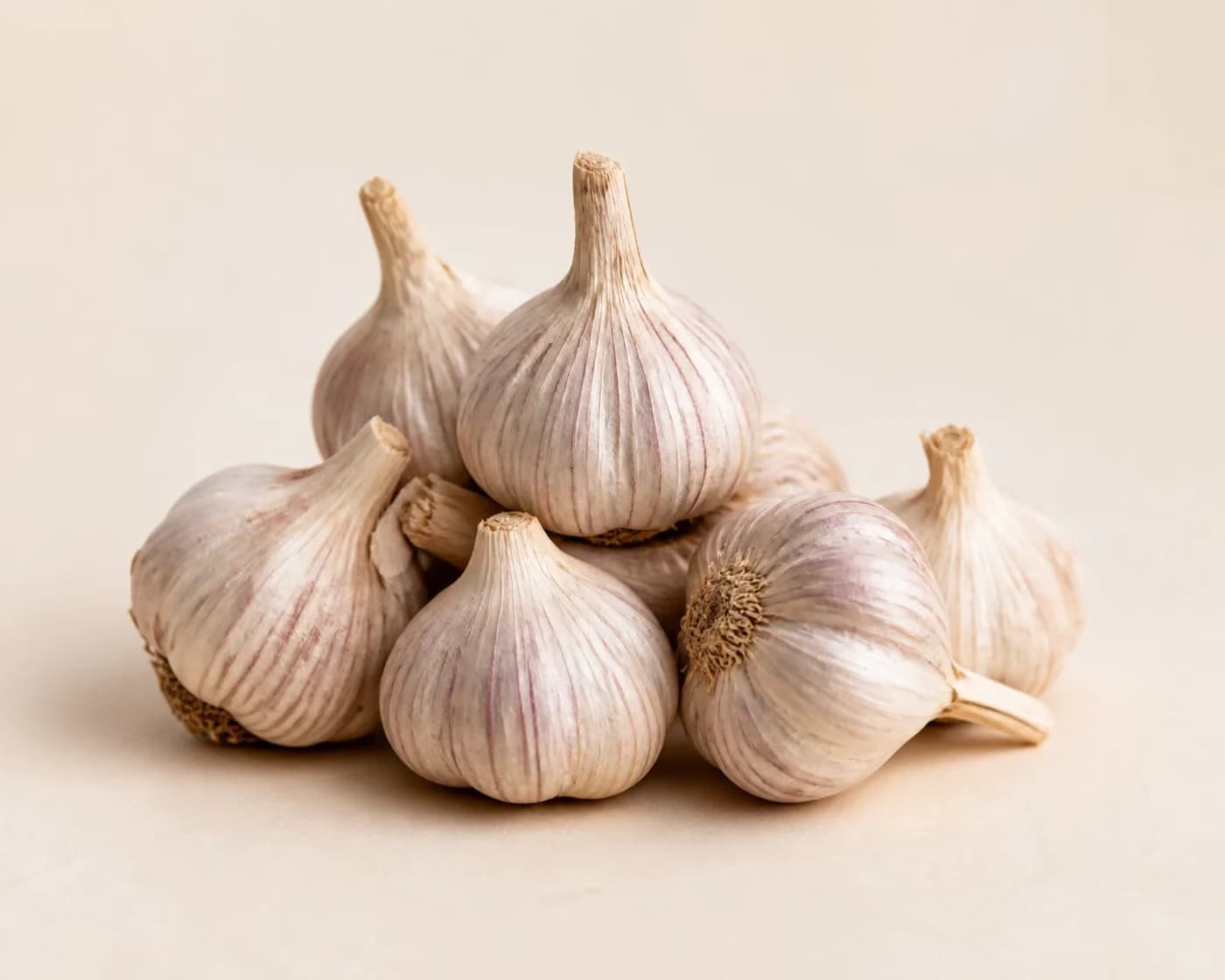 Fresh Desi Garlic arranged on a warm off-white surface.