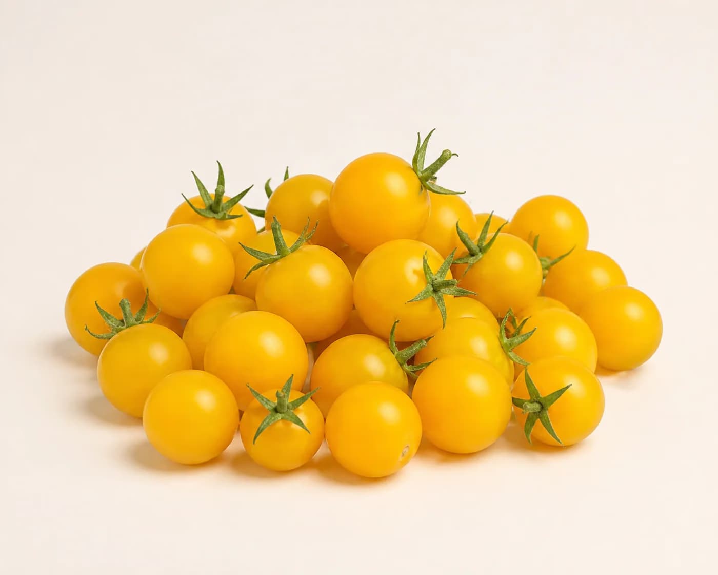 Fresh Yellow Cherry Tomato arranged on a warm off-white surface.