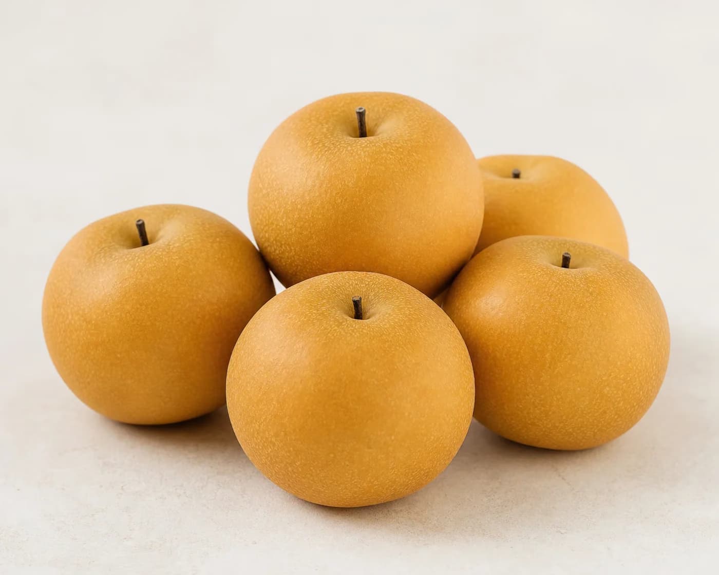Fresh Nashi Pear arranged on a warm off-white surface.