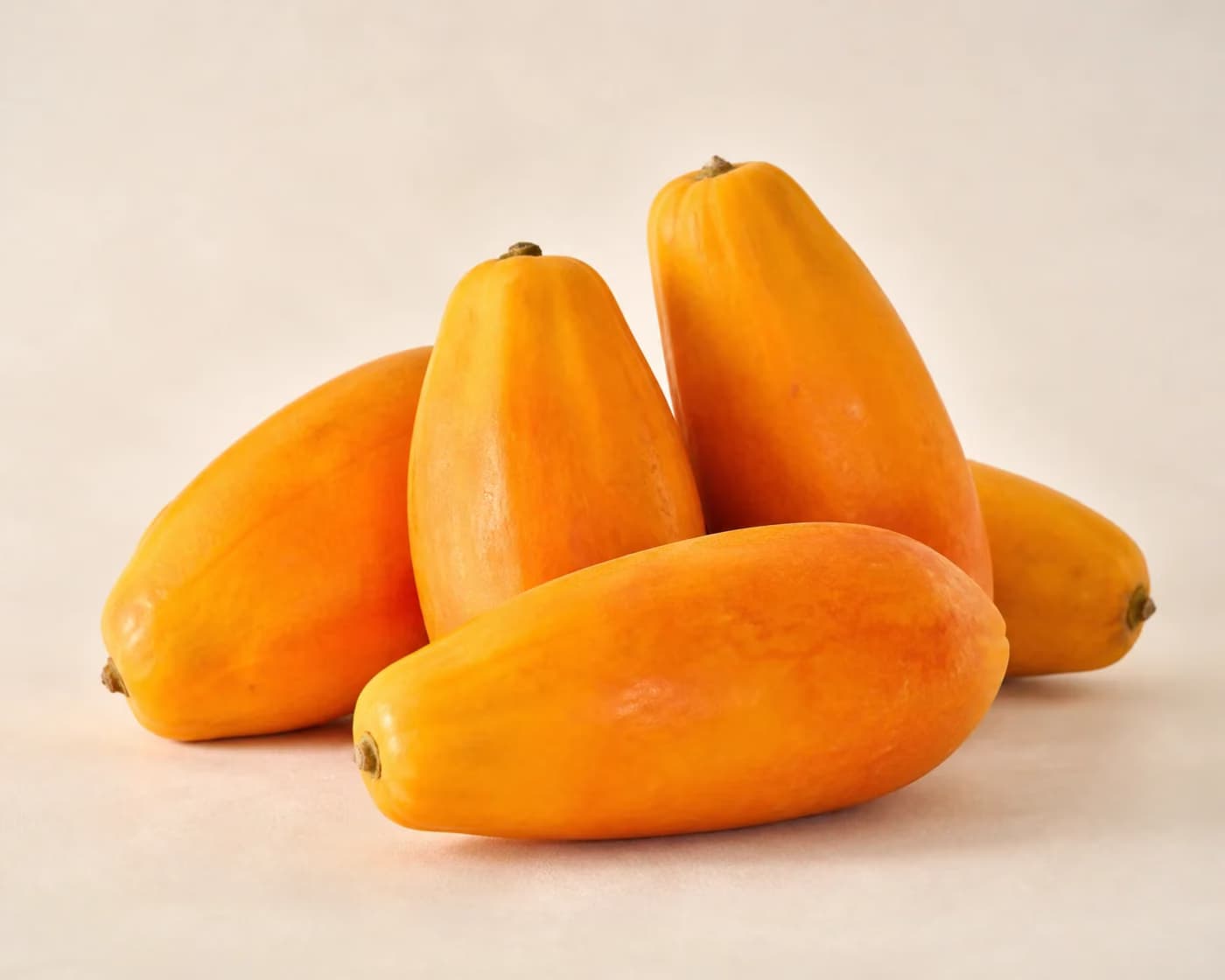 Fresh Red Lady Papaya arranged on a warm off-white surface.