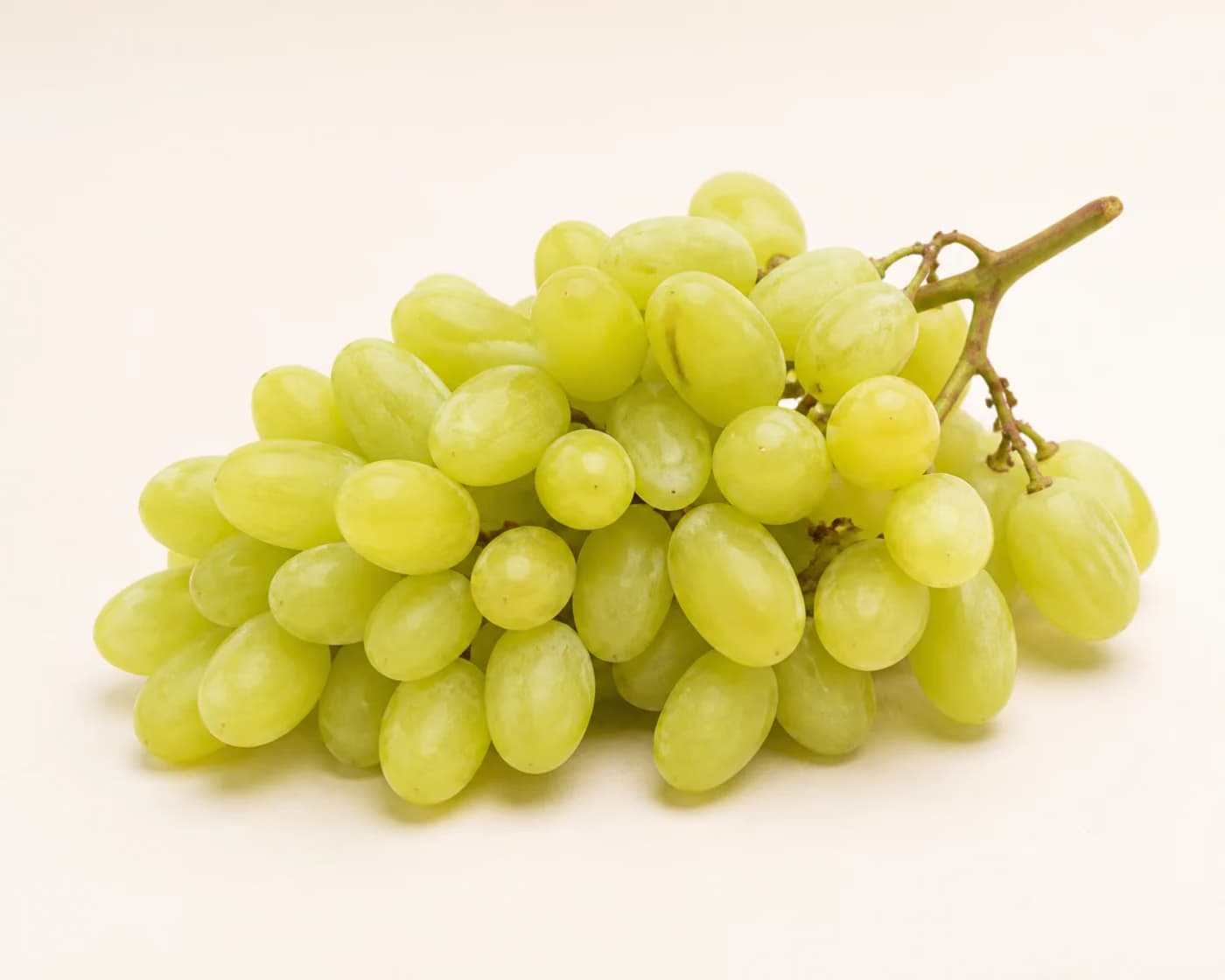 Fresh Sharad Seedless Grapes arranged on a warm off-white surface.