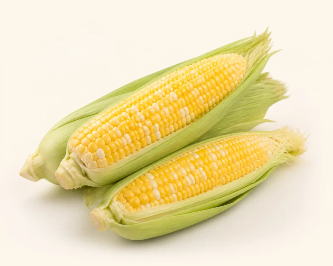 Fresh Bicolour Sweet Corn arranged on a warm off-white surface.