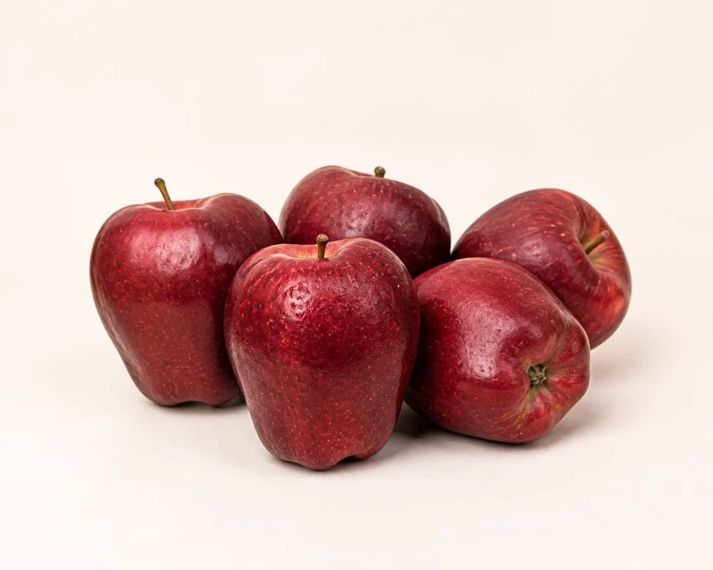 Fresh Washington Red Delicious Apple arranged on a warm off-white surface.