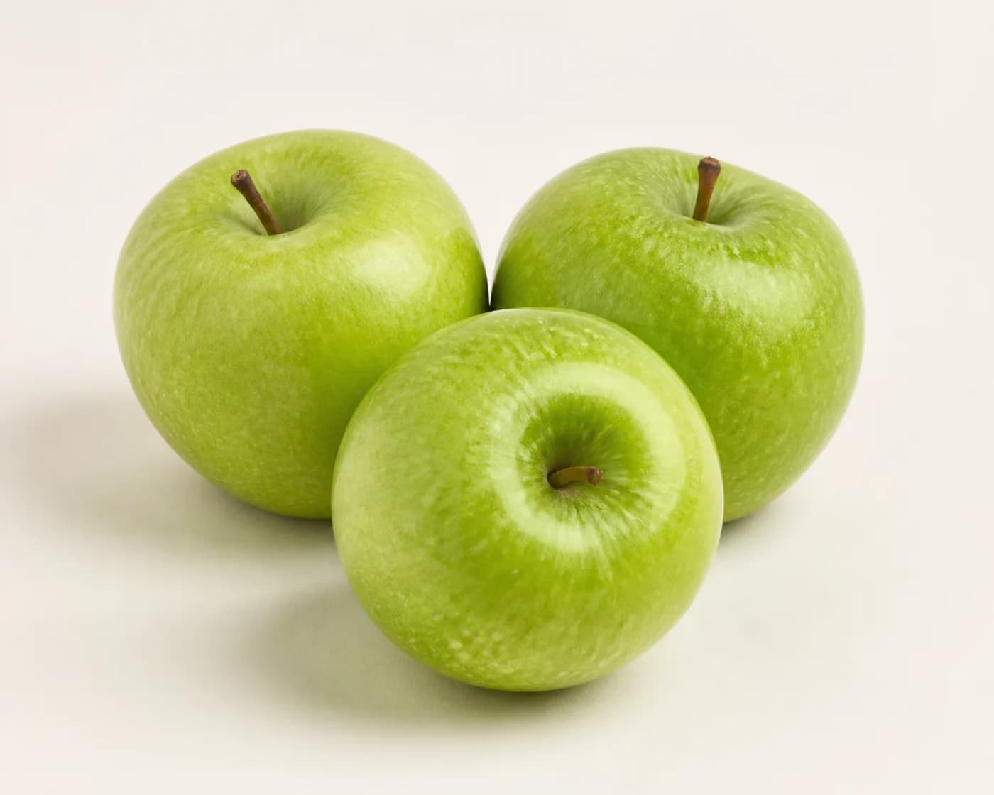 Fresh Granny Smith Apple arranged on a warm off-white surface.