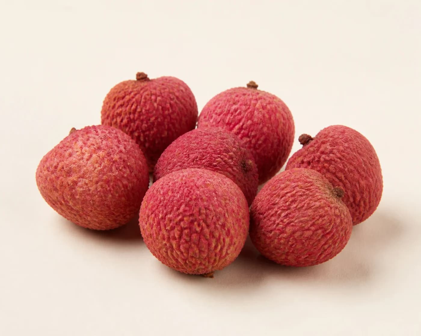 Fresh China Litchi arranged on a warm off-white surface.