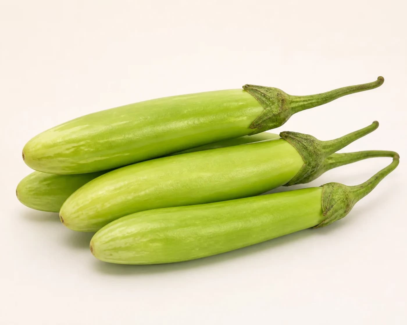 Fresh Green Long Brinjal arranged on a warm off-white surface.
