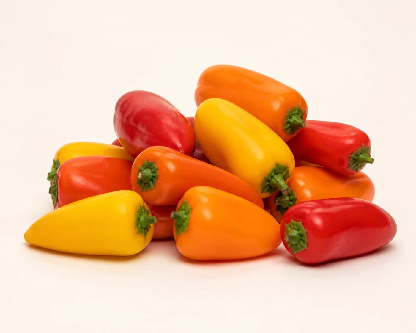 Fresh Mini Sweet Peppers arranged on a warm off-white surface.