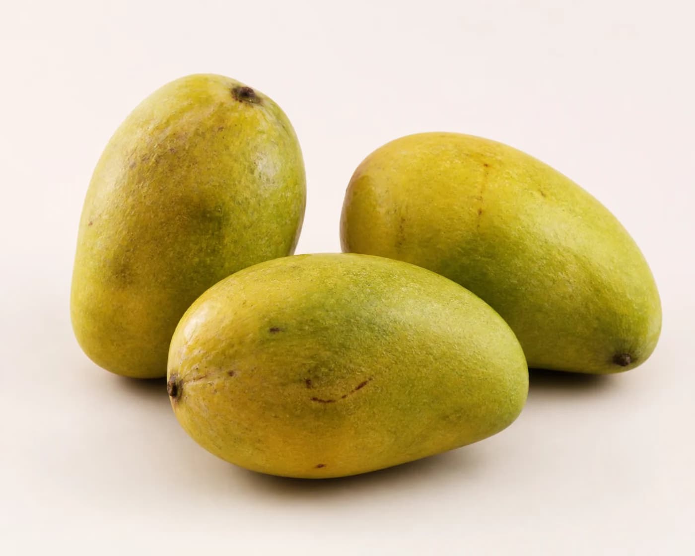 Fresh Langra Mango arranged on a warm off-white surface.