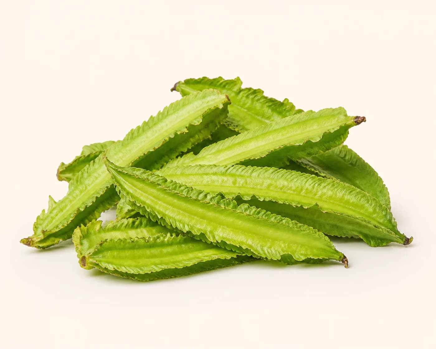 Fresh Winged Beans arranged on a warm off-white surface.
