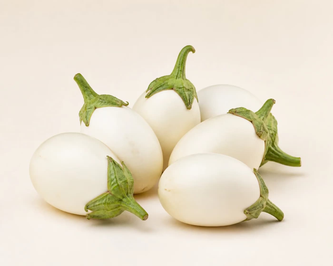 Fresh White Brinjal arranged on a warm off-white surface.
