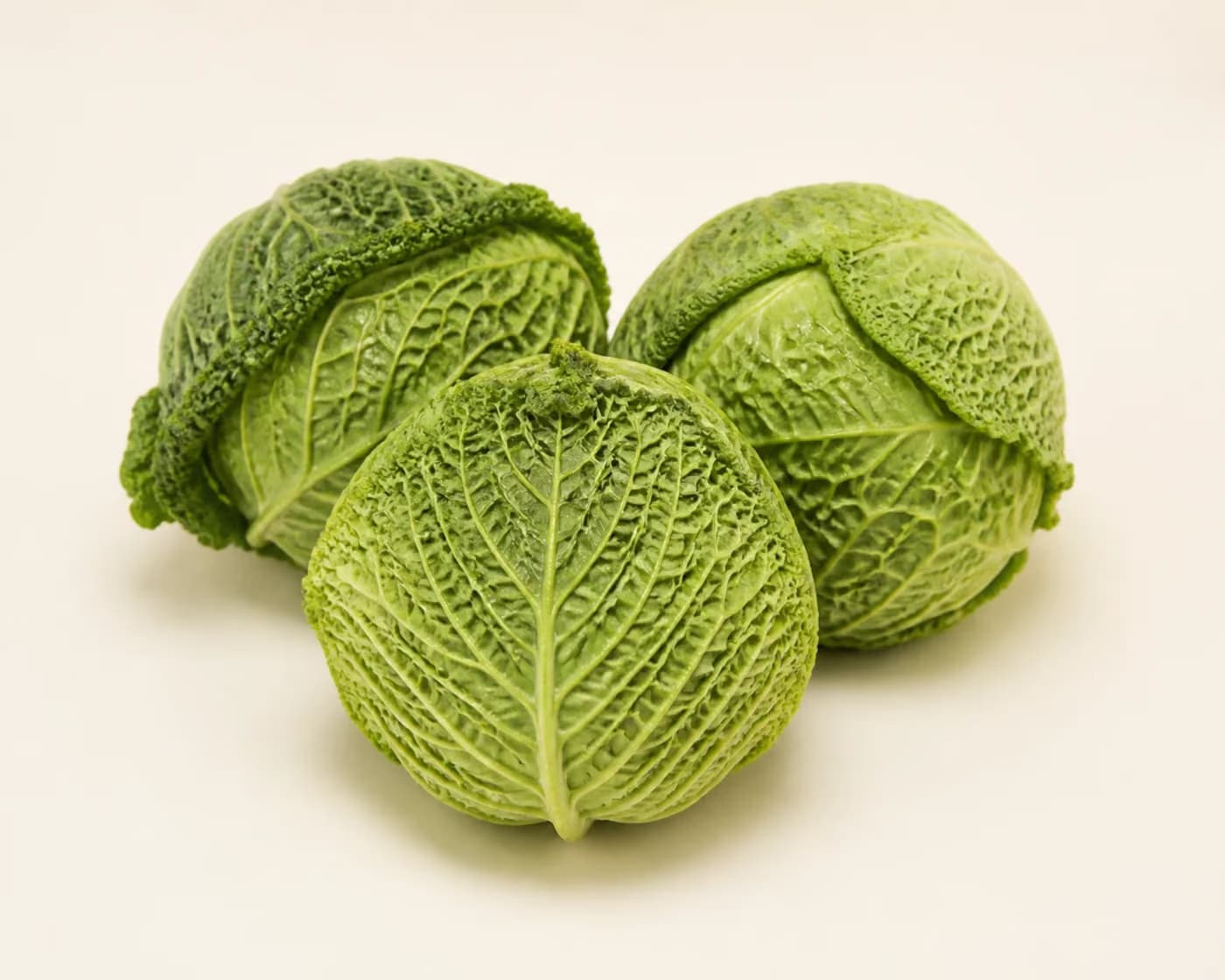 Fresh Savoy Cabbage arranged on a warm off-white surface.