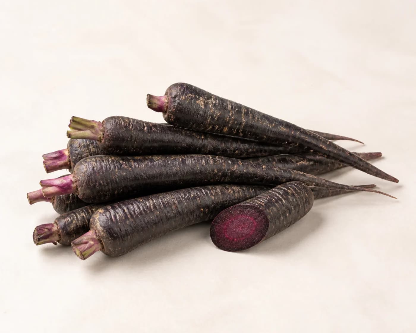 Fresh Purple Carrot arranged on a warm off-white surface.