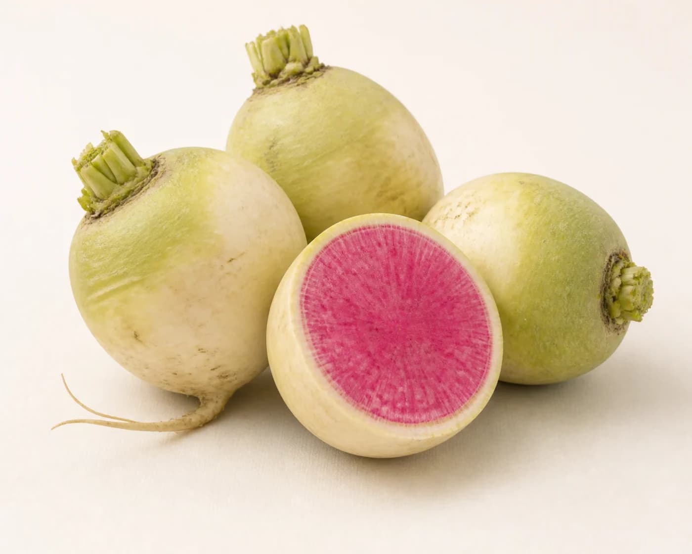 Fresh Watermelon Radish arranged on a warm off-white surface.