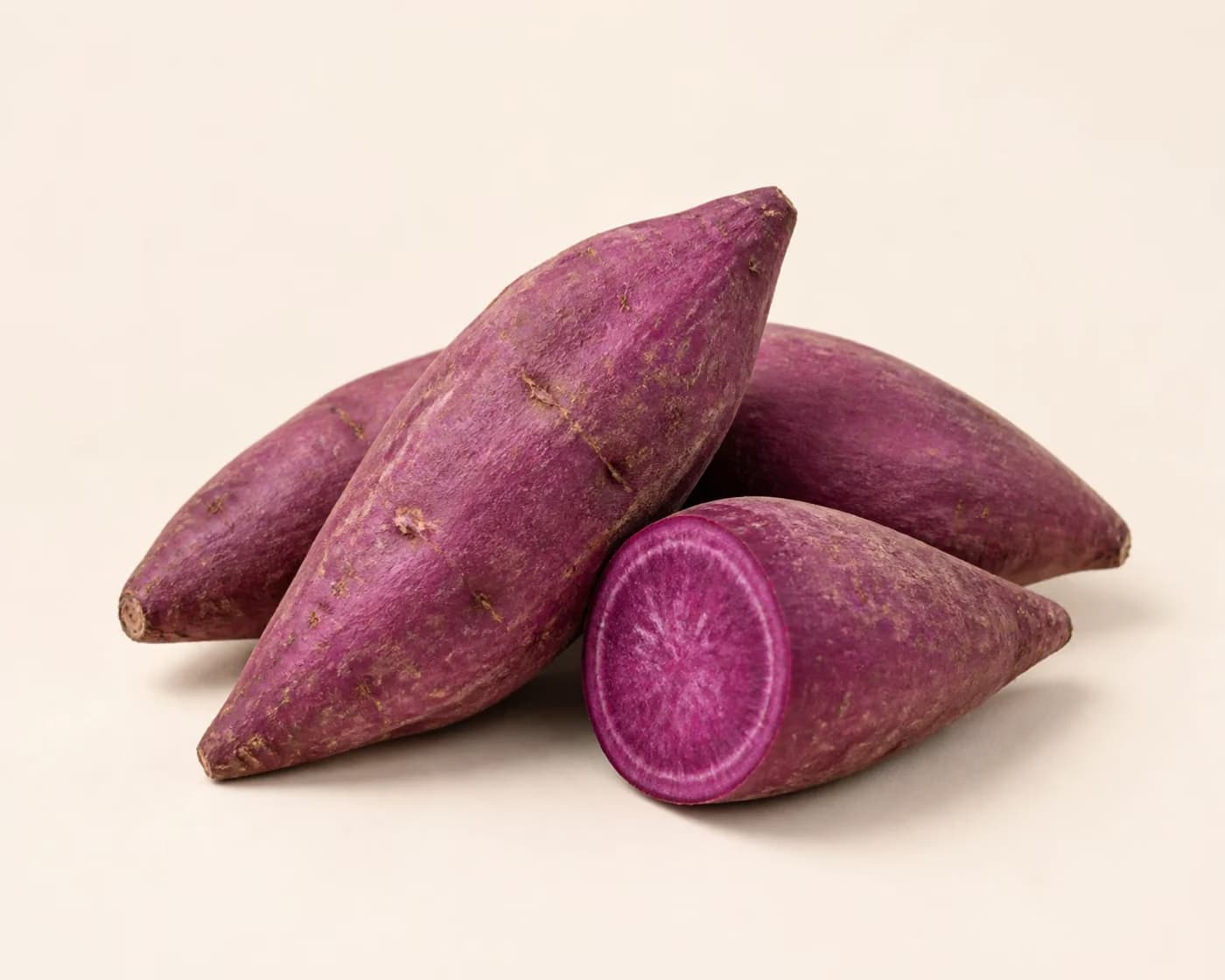 Fresh Purple Sweet Potato arranged on a warm off-white surface.