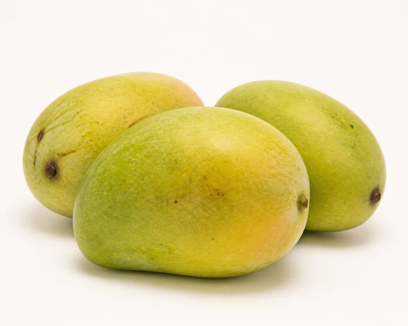 Fresh Malda Mango arranged on a warm off-white surface.
