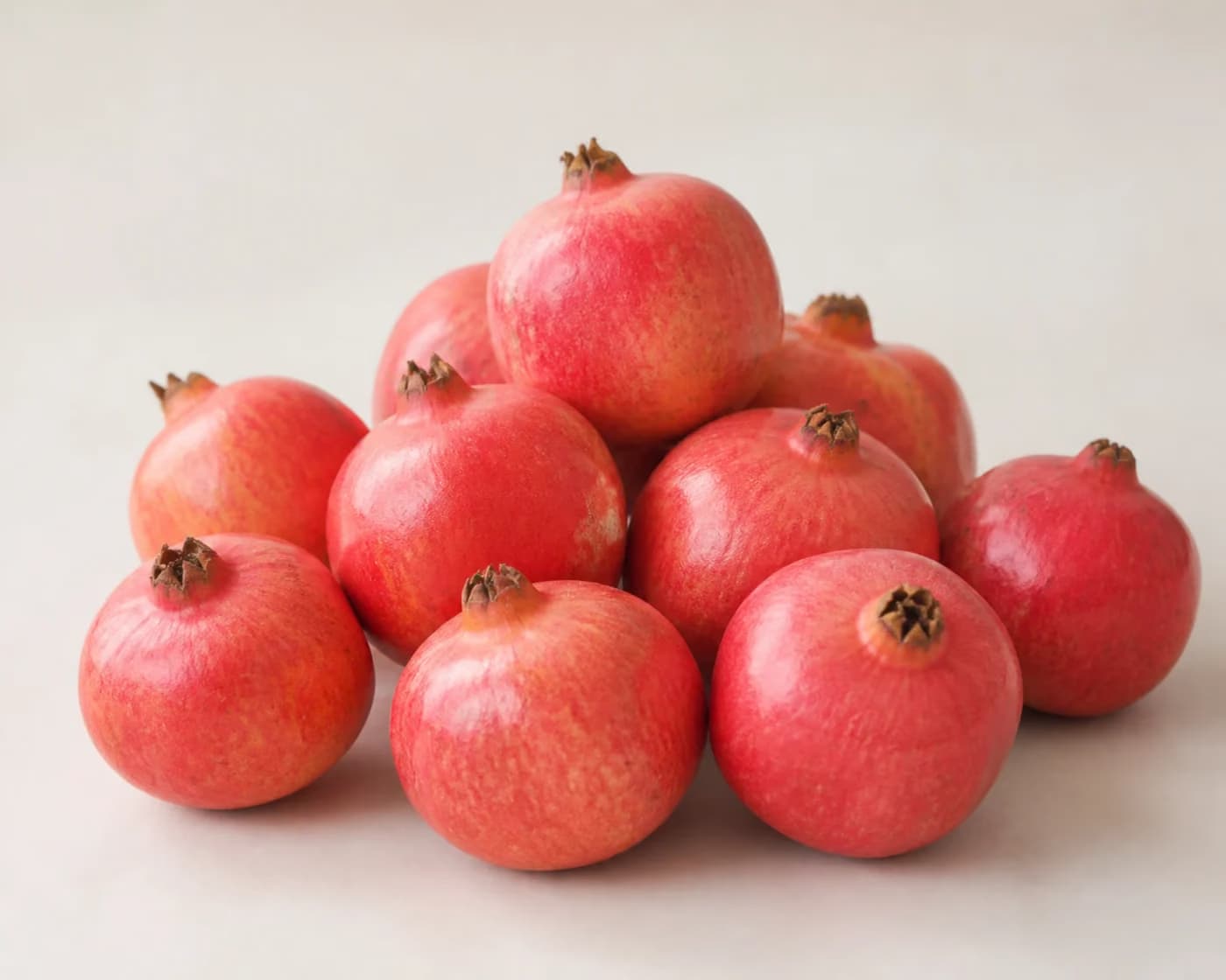 Fresh Ganesh Pomegranate arranged on a warm off-white surface.